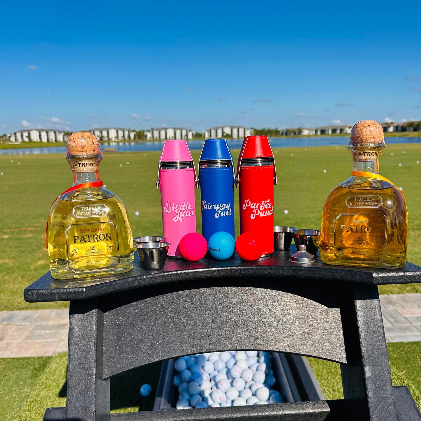 Flasks and alcohol bottles with shot glasses, on a golf course